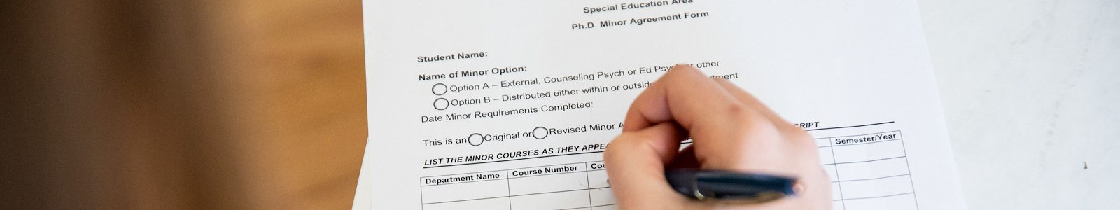hand with pen writing on form